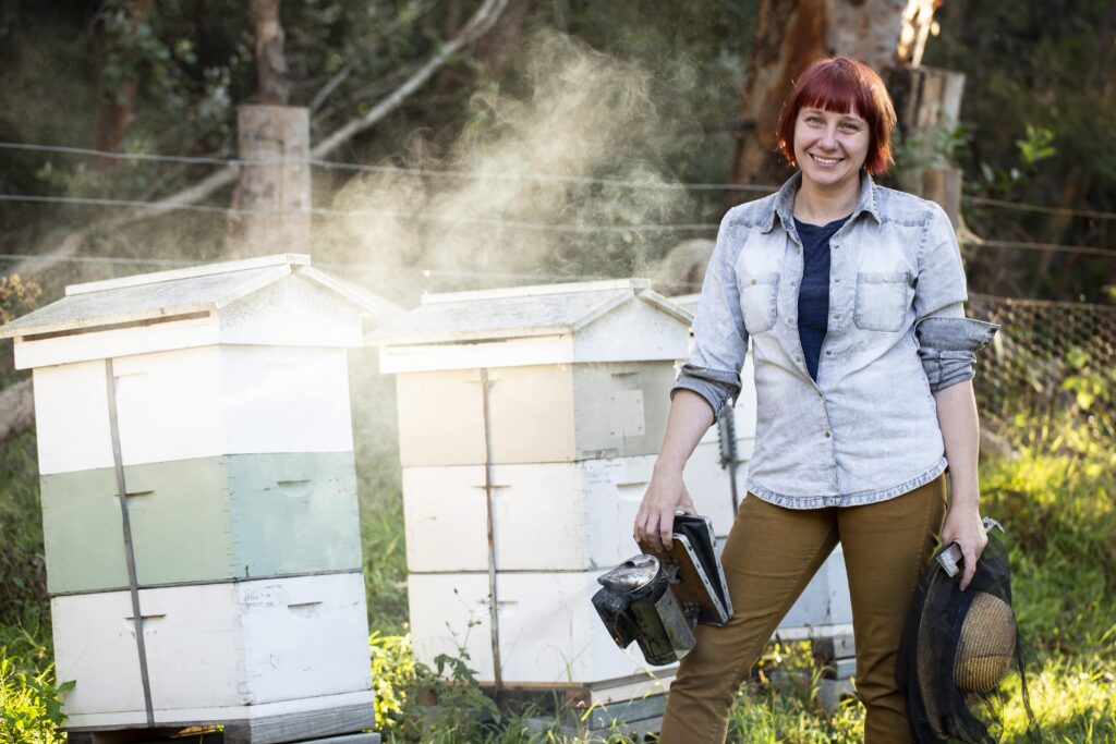 Experienced urban beekeeper Vicky Brown stands next to hives in a Urban Beehive Sydney-city apiary